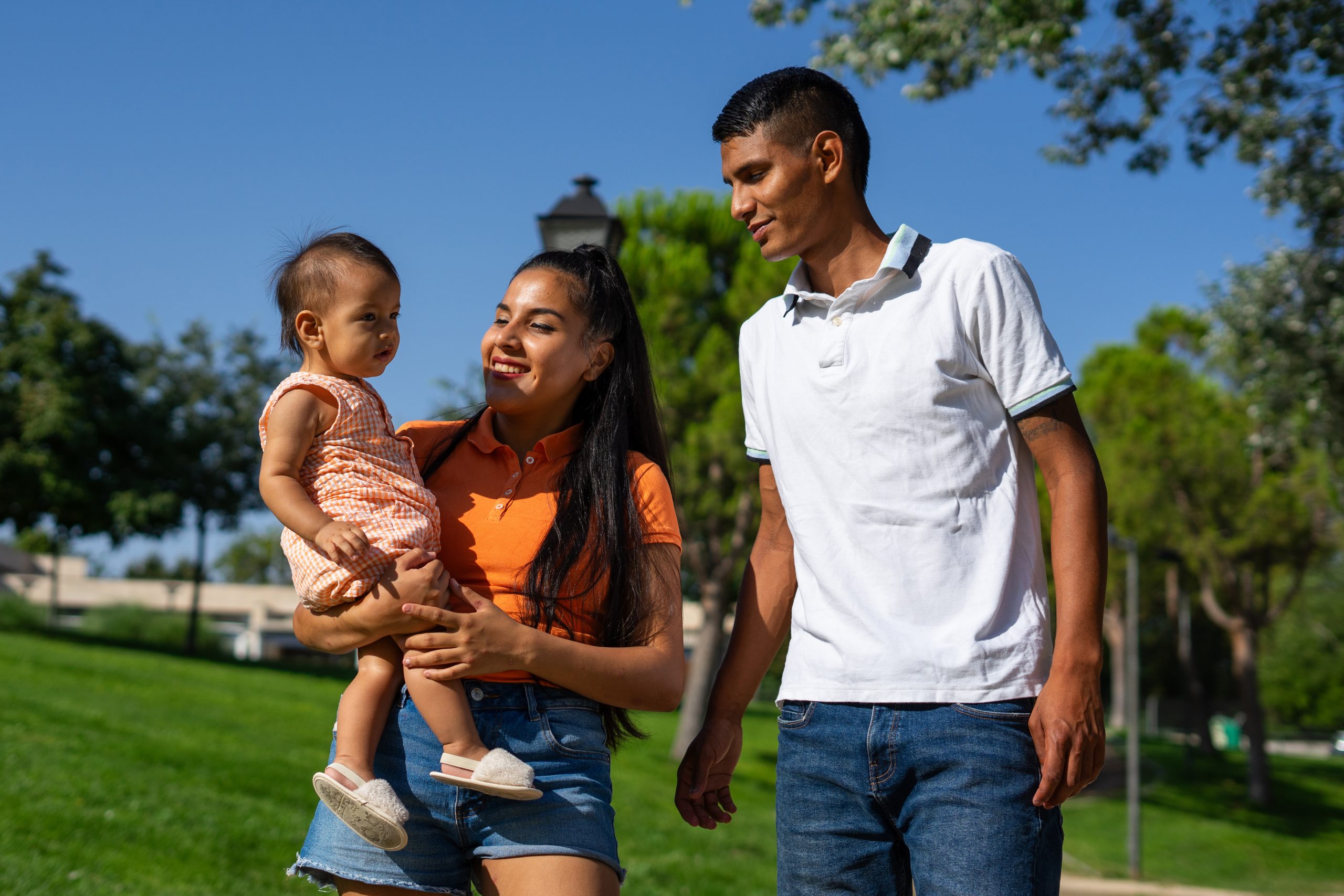 Young Latin family of father, mother and 1 year old baby in a park outdoors